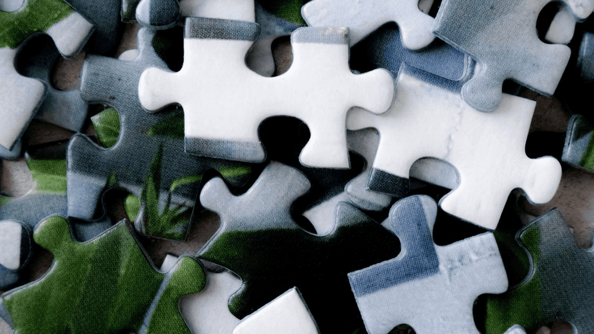 GreySuits-Feature-pexels-photo-30708396-636 | GreySuits Advisors | GreySuits Advisors Close-up of interlocking jigsaw puzzle pieces in blue, green, and white colors, some pieces joined together while others lay scattered.