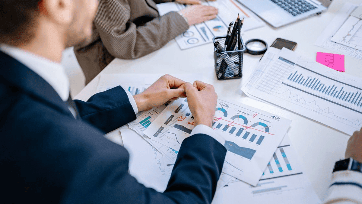 GreySuits-Feature-pexels-photo-7698819-640 | GreySuits Advisors | GreySuits Advisors Team members examine printed charts and graphs on a white table during a meeting.